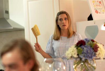 An Ideal Host woman stands with a small broom in her hand.