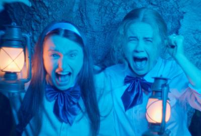 Two girls screaming at an off camera presence emitting blue light