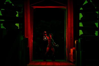 A person holds a lantern in the doorway