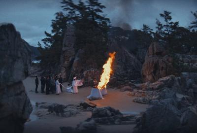 People in front of a funeral pyre on the beach 