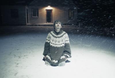Colt sits in the snow looking up at the night sky.