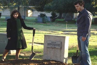 Burying The Ex man and woman stand with shovels at a grave