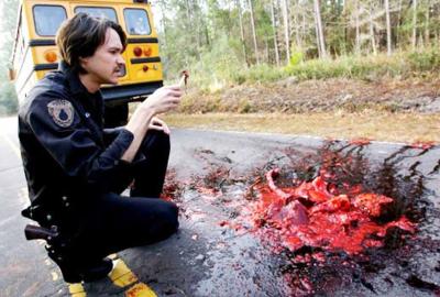 Cabin Fever 2: Spring Fever police looks at a piece of road kill on the road