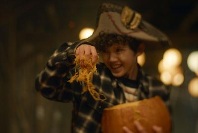 A young boy pulls the insides of the pumpkin out