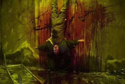 Curandero man hangs upside down against a bloody wall