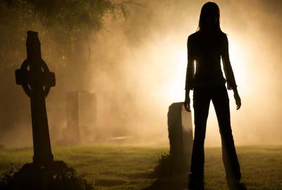 Forget Me Not woman stands in a cemetery at night