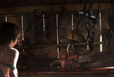 Leatherface film still boy looks at torturous tools in a shed.