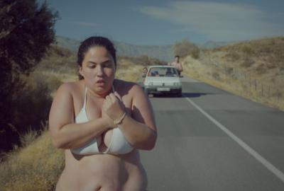 Piggy film still overweight young woman running in her bra and panties with a car behind her