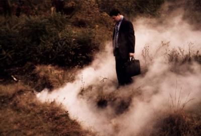 Sinkhole man stands in smoky grass