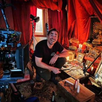 Will Kresch on the set of Alone Together, holding a knife and adjusting a shrine for filming.